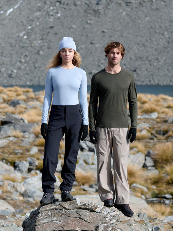 Two hikers in Icebreaker 200 Oasis merino base layers standing on a rocky ridge above a mountain lake