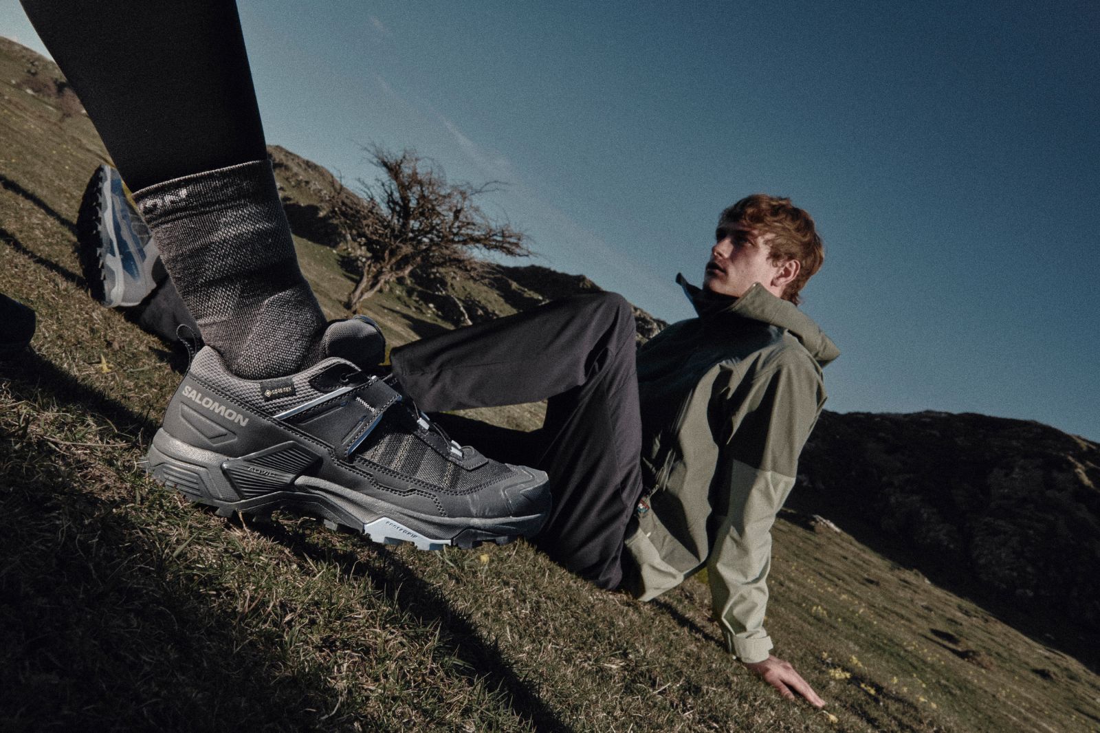Camper at dusk stepping out of a tent wearing Merrell shoes