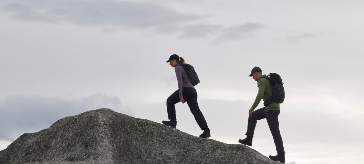 Two hikers in Icebreaker merino layers climbing a rocky ridge